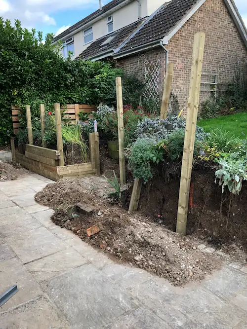 portrait view of installation of a flower bed with wooden beams sticking out of the mud