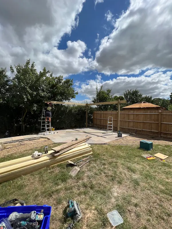 pergola being built in garden on top of grey and brown patio