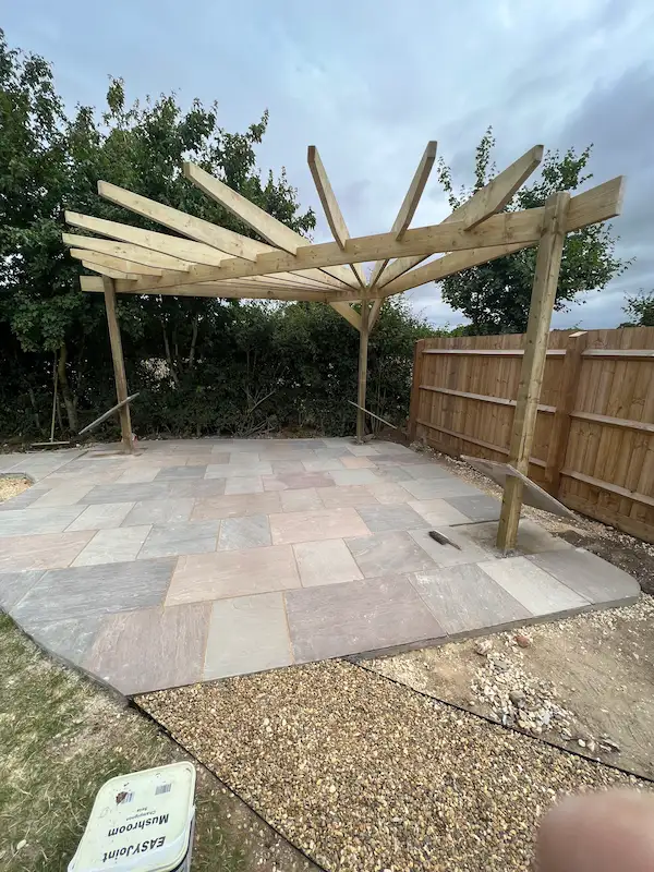 corner pergola in process of building on top of grey and brown patio